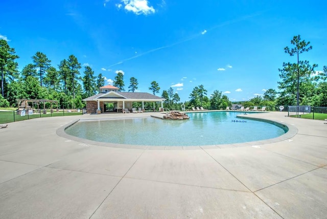 community pool with a gazebo, fence, and a patio area