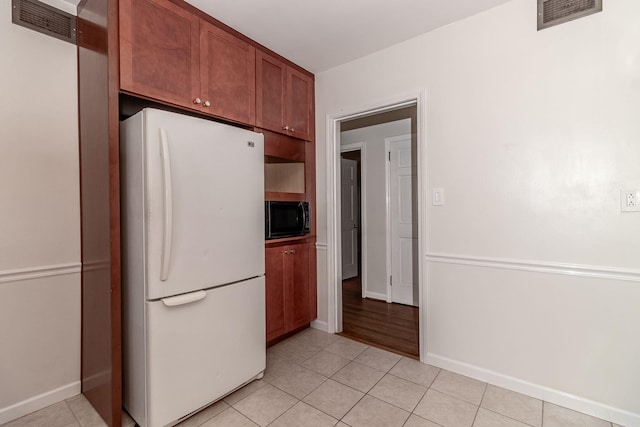 751 Lancaster Rd, Augusta, GA 30909 - kitchen featuring freestanding refrigerator, black microwave, light tile patterned flooring, and baseboards