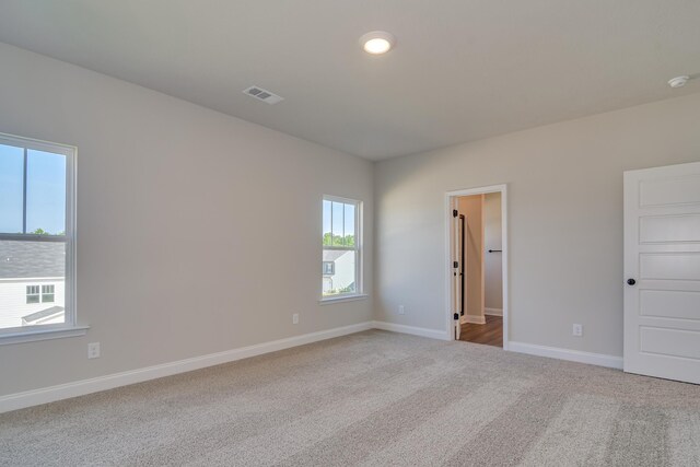 empty room with light carpet, visible vents, and baseboards