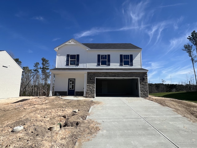 view of front of property featuring a garage, stone siding, board and batten siding, and concrete driveway