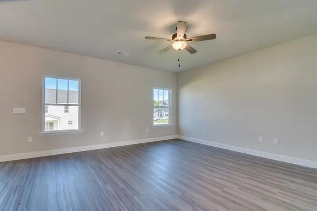 spare room featuring dark wood finished floors, a ceiling fan, and baseboards