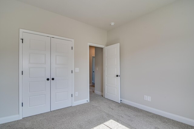 unfurnished bedroom featuring carpet, baseboards, and a closet