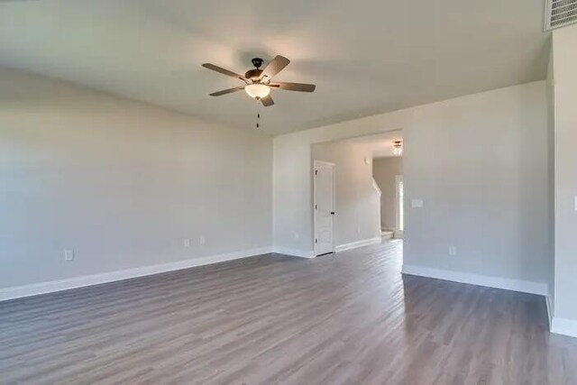 unfurnished room with a ceiling fan, dark wood-type flooring, baseboards, and visible vents