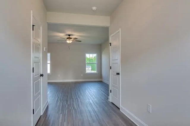 unfurnished room featuring a ceiling fan, baseboards, and dark wood-style flooring