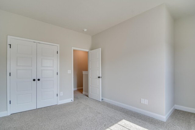 unfurnished bedroom with a closet, baseboards, and carpet