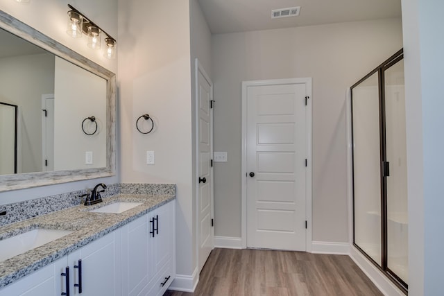 bathroom featuring a sink, visible vents, wood finished floors, and a stall shower