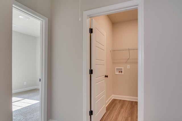 washroom featuring washer hookup, baseboards, and light wood finished floors