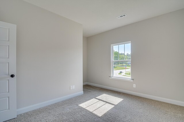 carpeted spare room with visible vents and baseboards