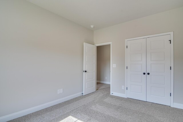 unfurnished bedroom featuring baseboards, light carpet, and a closet