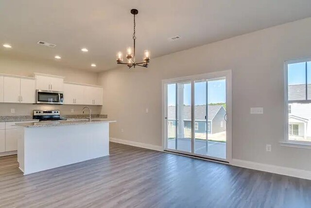 kitchen featuring a center island with sink, baseboards, dark wood-style flooring, a sink, and stainless steel appliances