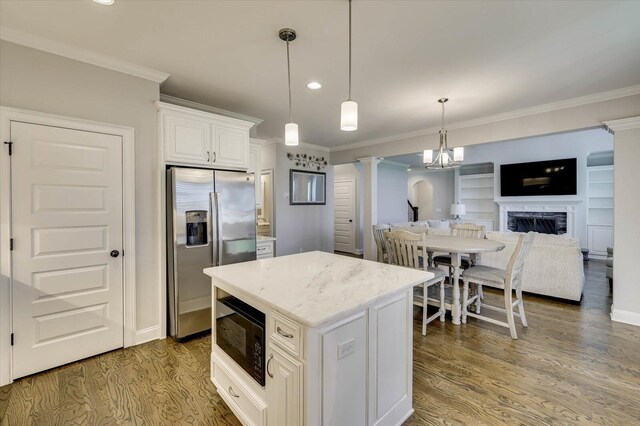 kitchen featuring black microwave, stainless steel fridge with ice dispenser, a center island, white cabinetry, and hanging light fixtures