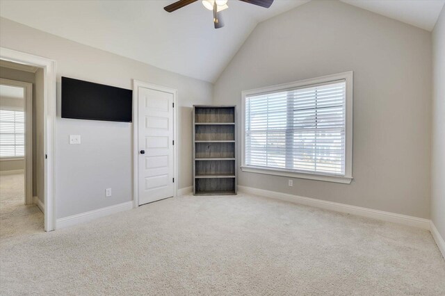 unfurnished bedroom with ceiling fan, lofted ceiling, light carpet, and multiple windows