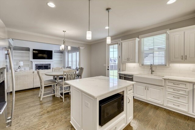 kitchen with sink, decorative light fixtures, a kitchen island, white cabinetry, and black microwave