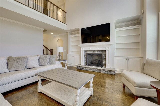 living room featuring dark hardwood / wood-style flooring, a fireplace, a high ceiling, and built in features