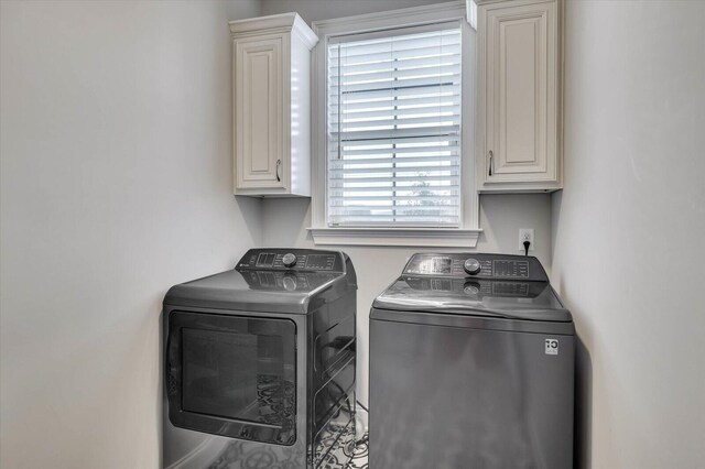 clothes washing area featuring cabinets and washing machine and clothes dryer