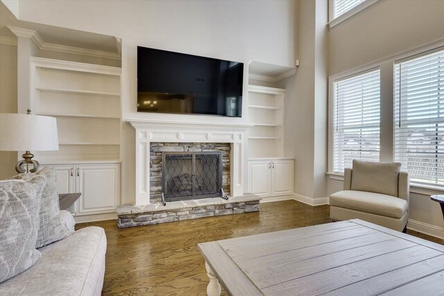 living room featuring a fireplace, built in shelves, dark hardwood / wood-style floors, and ornamental molding