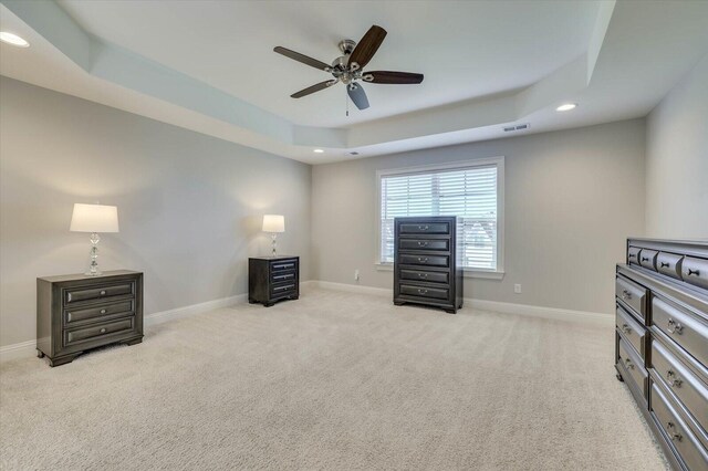 carpeted bedroom with a raised ceiling and ceiling fan