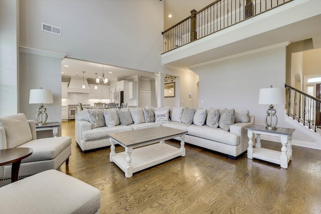 living room with hardwood / wood-style flooring, a towering ceiling, and a chandelier