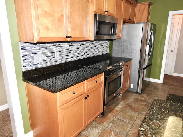 kitchen with dark stone countertops, appliances with stainless steel finishes, and tasteful backsplash