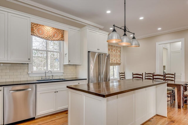 721 Bishops Cir, Evans, GA 30809 - kitchen featuring appliances with stainless steel finishes, sink, white cabinets, hanging light fixtures, and ornamental molding