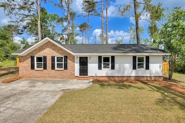 single story home featuring a shingled roof, driveway, brick siding, and a front yard