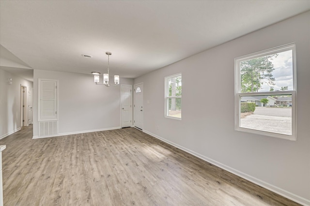 unfurnished dining area featuring baseboards, wood finished floors, and a chandelier