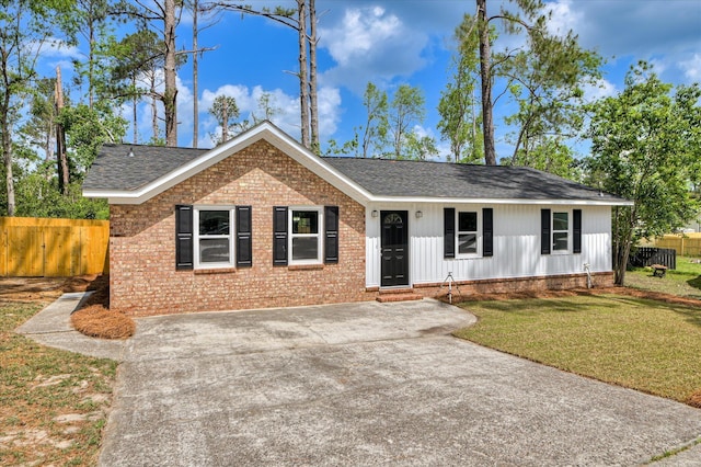 ranch-style home featuring roof with shingles, brick siding, fence, a front lawn, and concrete driveway