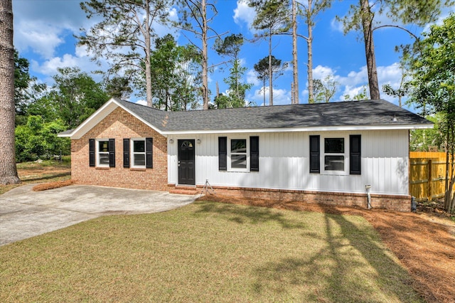 ranch-style house featuring brick siding, fence, roof with shingles, and a front lawn
