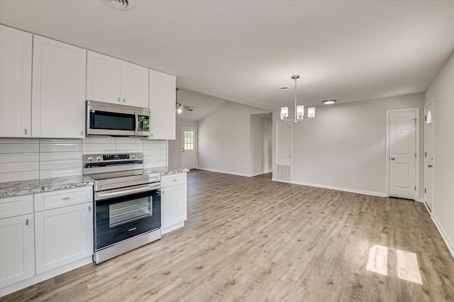 kitchen with appliances with stainless steel finishes, white cabinets, light wood-style flooring, and a notable chandelier