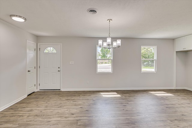 entryway with visible vents, baseboards, wood finished floors, and an inviting chandelier