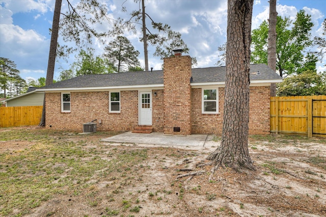 rear view of house with fence private yard, brick siding, a chimney, and a patio
