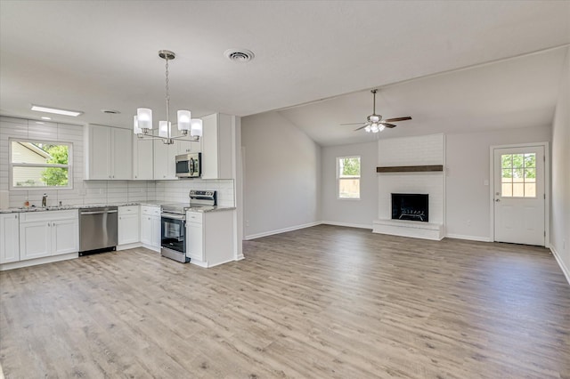 kitchen with baseboards, light wood-type flooring, white cabinetry, light stone counters, and stainless steel appliances