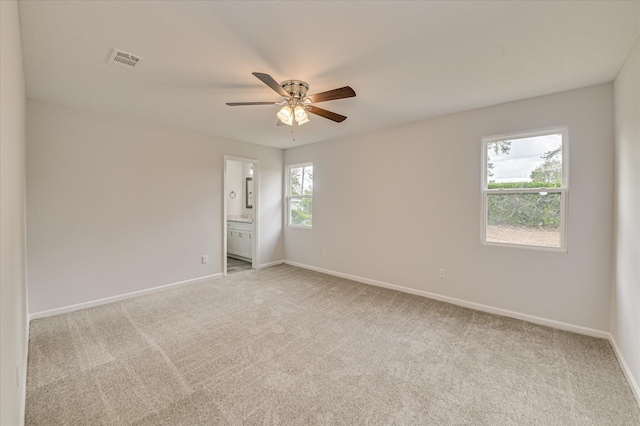 carpeted spare room featuring baseboards, a ceiling fan, and visible vents