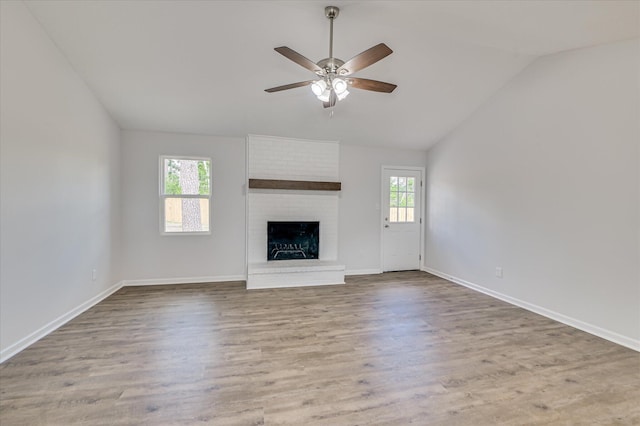 unfurnished living room featuring ceiling fan, a fireplace, vaulted ceiling, wood finished floors, and baseboards