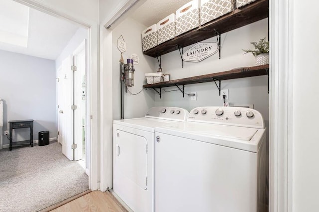 laundry area with washer and dryer and light hardwood / wood-style flooring