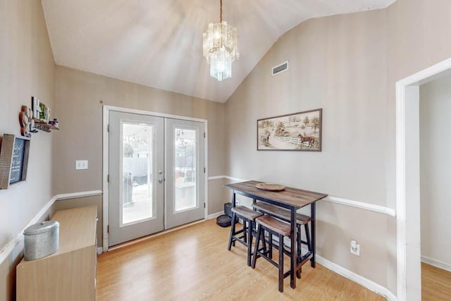 doorway featuring vaulted ceiling, a chandelier, light wood-type flooring, and french doors