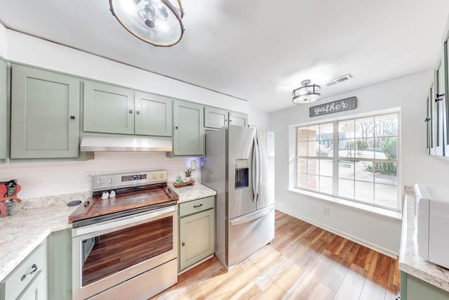 kitchen featuring green cabinetry, appliances with stainless steel finishes, light stone countertops, and light hardwood / wood-style floors