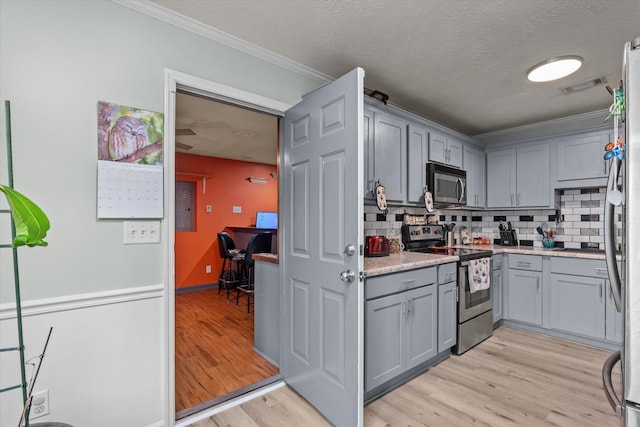 1737 Tamarind Way, Augusta, GA 30906 - kitchen featuring appliances with stainless steel finishes, gray cabinetry, light wood-type flooring, ornamental molding, and decorative backsplash
