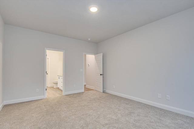 unfurnished bedroom featuring light carpet and connected bathroom