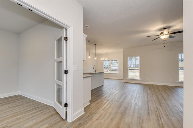 interior space with ceiling fan with notable chandelier, sink, and light hardwood / wood-style flooring