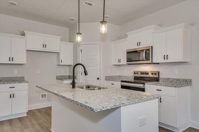 kitchen featuring white cabinets, decorative light fixtures, an island with sink, and appliances with stainless steel finishes