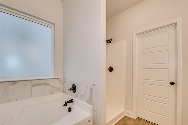 bathroom featuring plus walk in shower and hardwood / wood-style floors