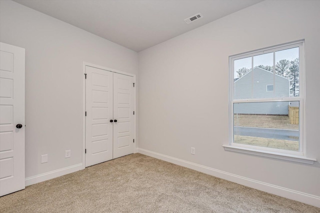 unfurnished bedroom with light carpet and a closet