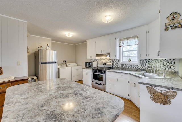 kitchen featuring under cabinet range hood, stainless steel appliances, separate washer and dryer, a sink, and light wood-style floors