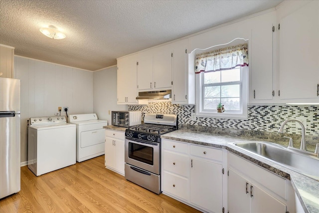 kitchen with light wood finished floors, appliances with stainless steel finishes, under cabinet range hood, separate washer and dryer, and a sink