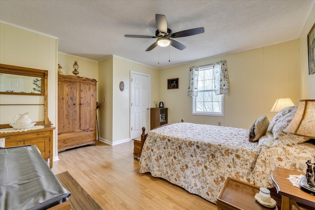 bedroom with baseboards, a ceiling fan, ornamental molding, a textured ceiling, and light wood-type flooring