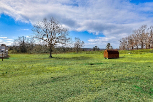 view of yard with an outbuilding, a rural view, and a storage shed