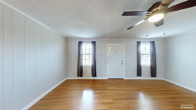 interior space featuring light wood-style flooring, ornamental molding, and a textured ceiling