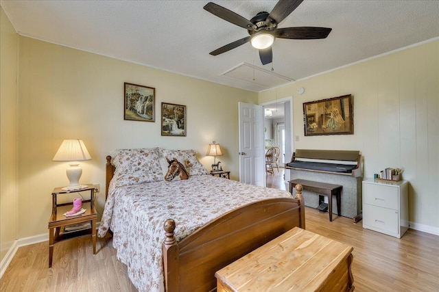 bedroom featuring attic access, light wood-style flooring, and a textured ceiling