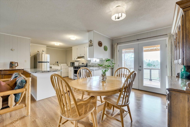 dining room featuring ornamental molding, french doors, light wood-style flooring, and a textured ceiling